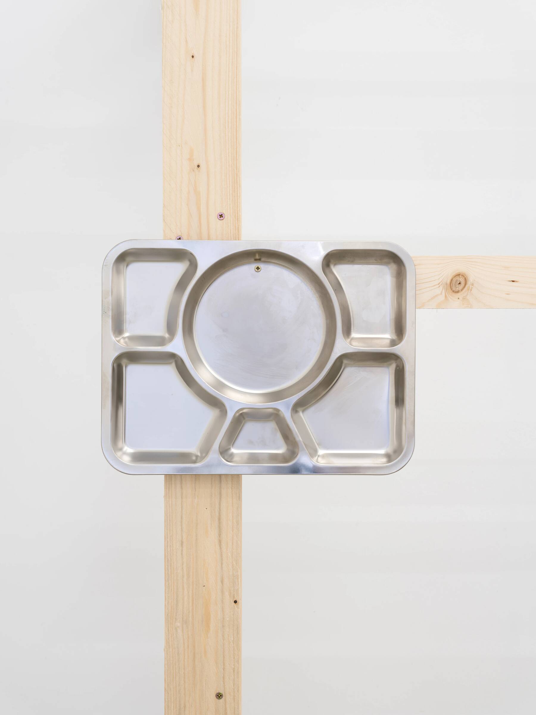 Edelstahl-Tablett mit sechs Fächern, montiert auf zwei sich kreuzenden Holzlatten an einer weißen Wand.